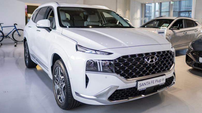 A white 2023 Hyundai Santa Fe Plug-in Hybrid SUV on display indoors