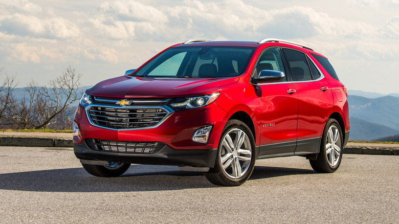 Red 2021 Chevrolet Equinox parked on concrete with mountains behind it.
