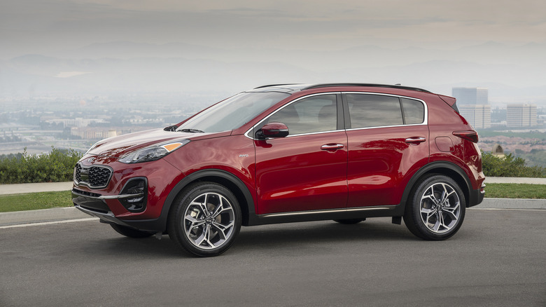 Red 2021 Kia Sportage parked on a road overlooking a cityscape.