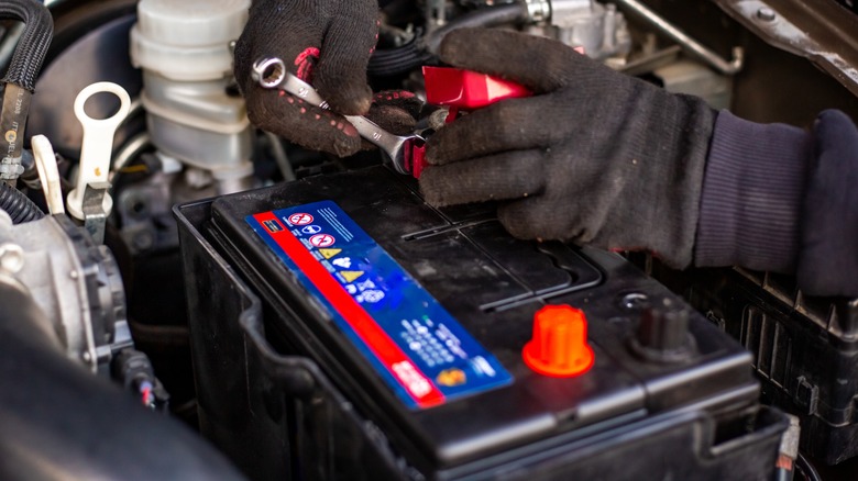 Replacing a car battery while wearing gloves.