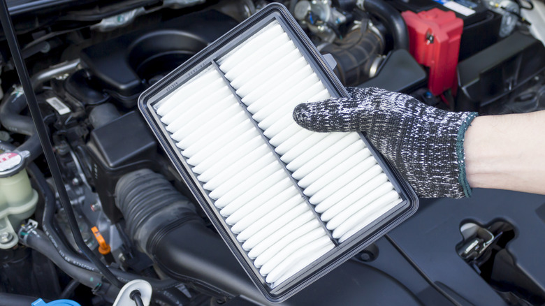 A hand holding a clean engine air filter.