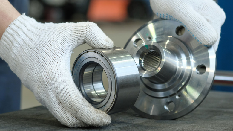 The bearing and wheel hub are in the hands of an auto mechanic.
