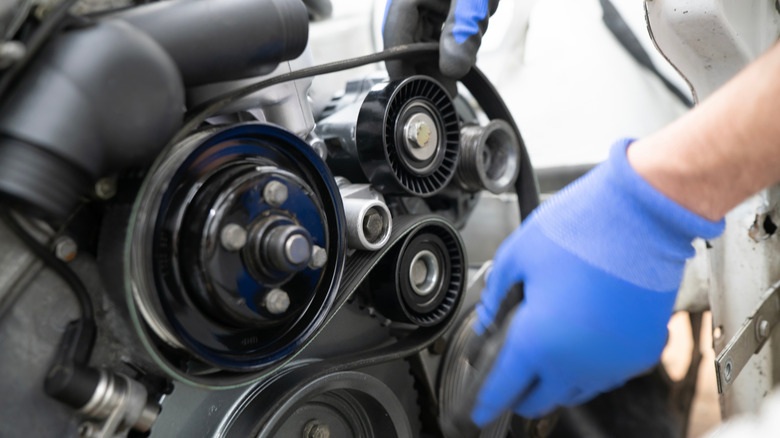 Mechanic working on car timing belt replacement under the hood