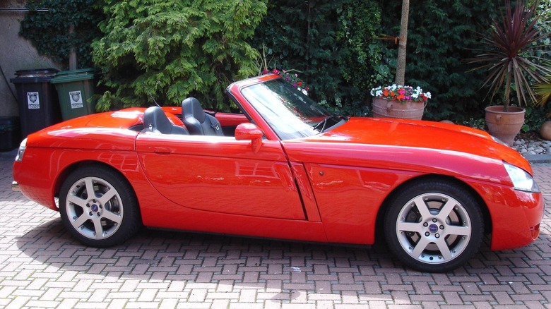 The sun glints off of a bright red Jensen S-V8 parked in a driveway.