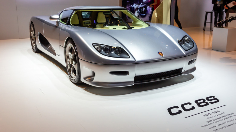 A silver Koenigsegg CC8S parked indoors at an auto show.