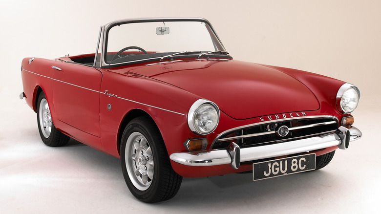 A red Sunbeam Tiger convertible with the top down against a white background.