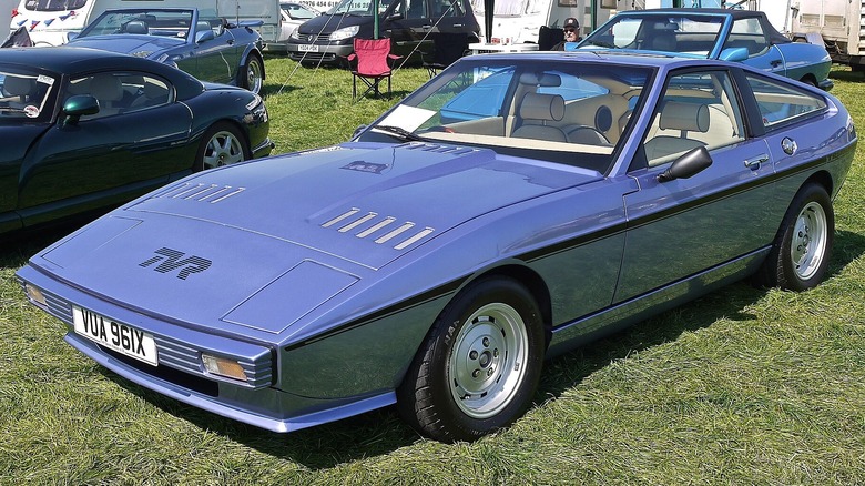 A light blue TVR Tasmin parked on the grass.
