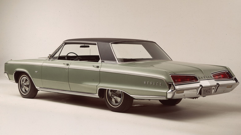 A light green, four-door Dodge Monaco with a black roof pictured from the rear.