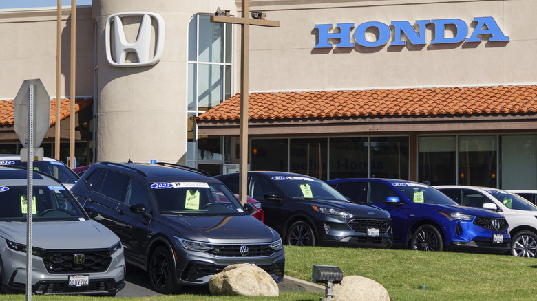 Several used cars sit on a Honda dealership lot.