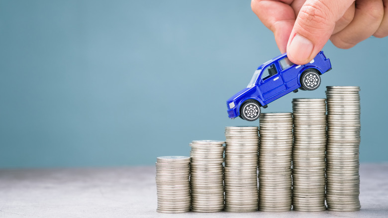 A blue toy car is carried down descending stacks of coins.
