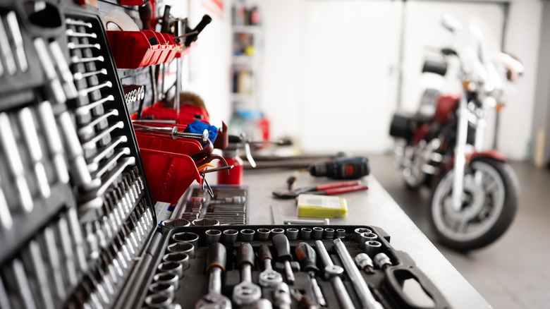 A socket set appears in the foreground with a motorcycle nearby.