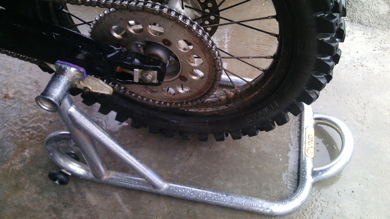 A paddock stand holds a motorcycle's rear wheel.