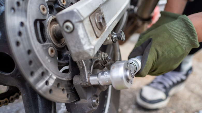 A person using a torque wrench to tighten a motorcycle bolt.