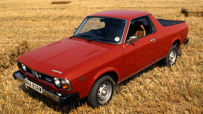 Red Subaru BRAT parked in a hay field