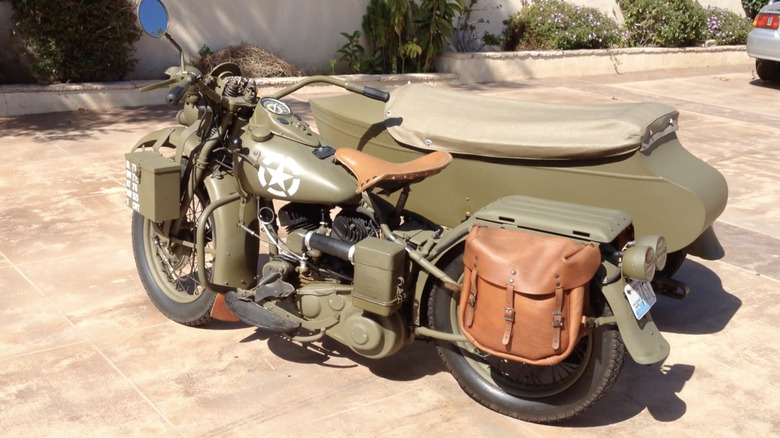 A 1942 Harley-Davidson WLA Liberator with a sidecar attachment parked on a sunny day on a concrete lot.