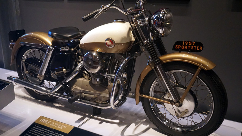 A gold 1957 Harley-Davidson XL Sportster with chrome accents in a museum.