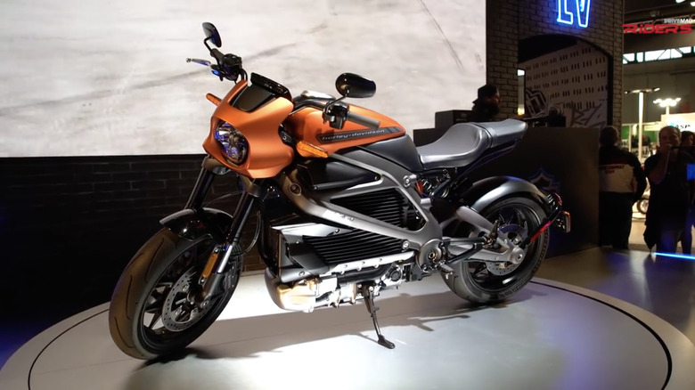 An orange 2019 Harley-Davidson LiveWire on a showroom floor with a brick background.