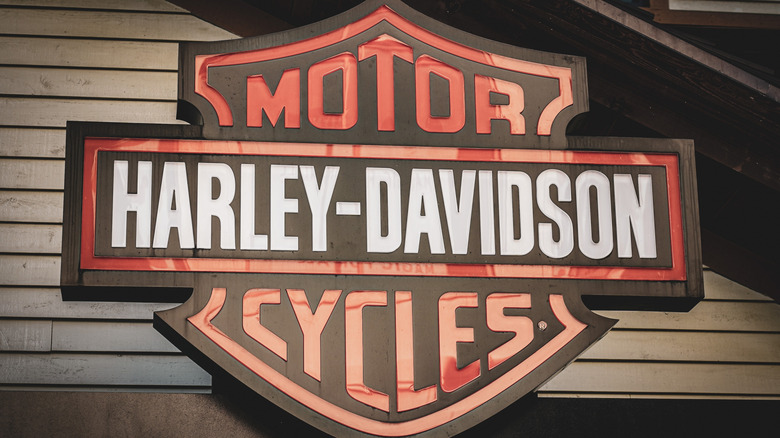 A Harley-Davidson sign hung in front of a wooden backdrop.