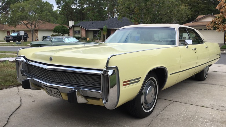 Pale yellow 1973 Imperial LeBaron sedan seen from front left parked in a driveway