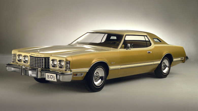 Gold 1976 Ford Thunderbird coupe seen from left fron parked in studio