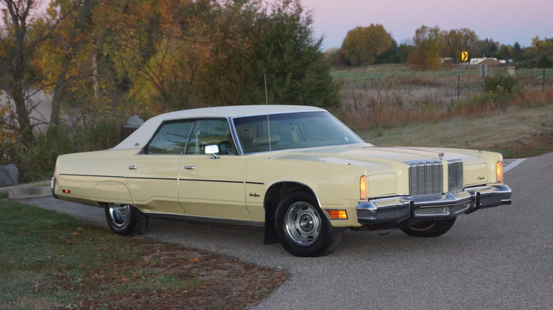 Pale yellow 1978 Chrysler New Yorker Brougham seen from right front parked near fields on an autumn evening