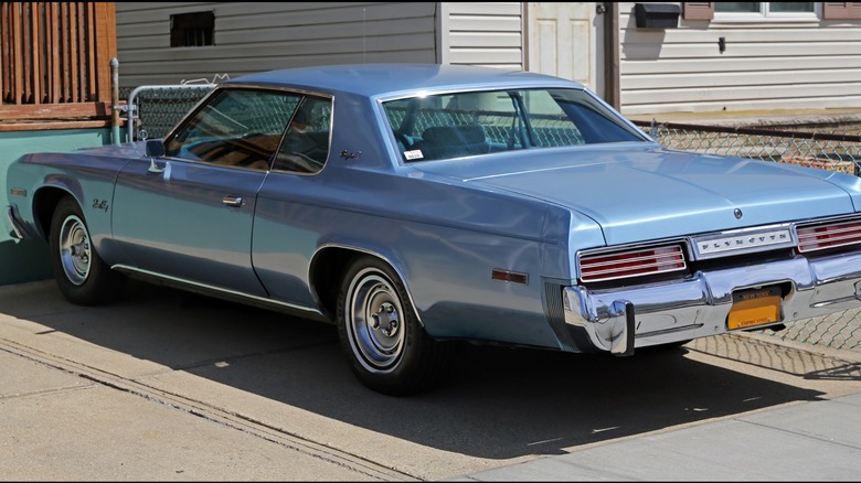 Blue 1977 Plymouth Gran Fury Brougham coupe seen from left rear parked in a driveway