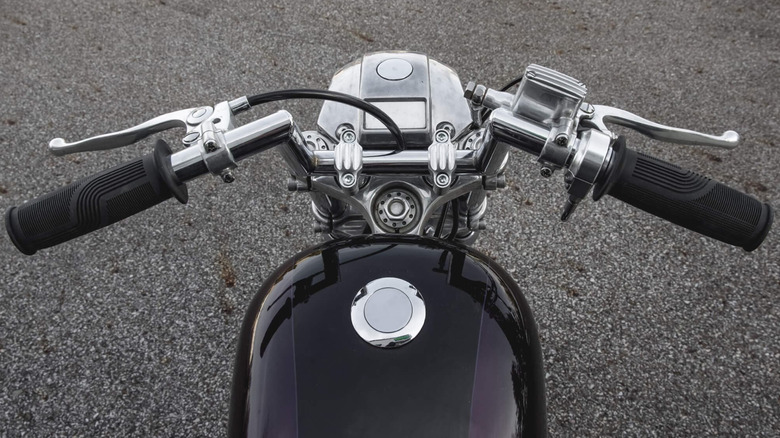 Motorcycle handlebars with aftermarket risers are shot from the rider's point of view.