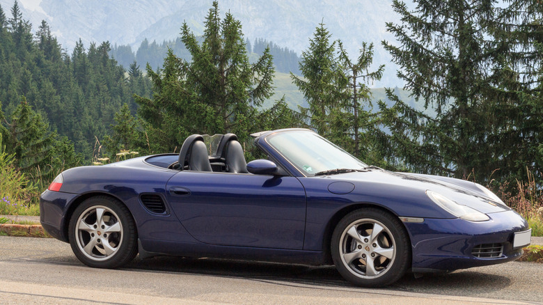 Dark blue convertible first-generation Porsche Boxster parked on the side of a mountain road