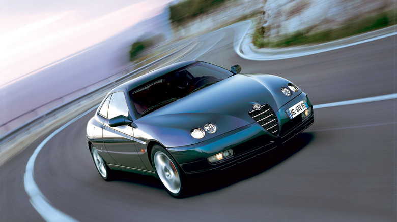 An Alfa Romeo 916 GTV driving down a cliffside road