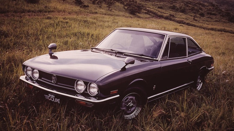 An Isuzu 117 Coupé in a field