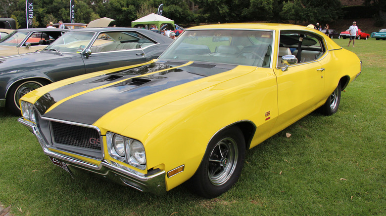 Yellow 1970 Buick GS 455 coupe left from three-quarter view parked at outdoor car show