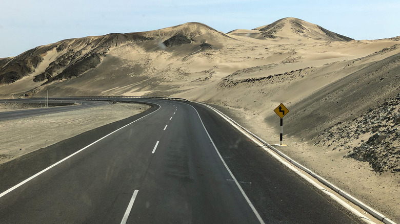 a curve on empty section of the Pan-American Highway in Peru, South America, with hills in background