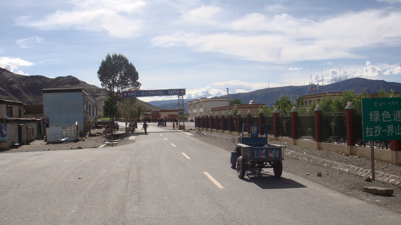China's National Highway 219, with trucks and people crossing and mountains in background.