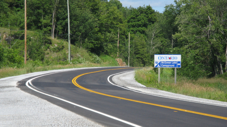 Trans Canada Highway in Ontario with plentiful trees and sign reading "Ontario: McGowan Lake Campground"