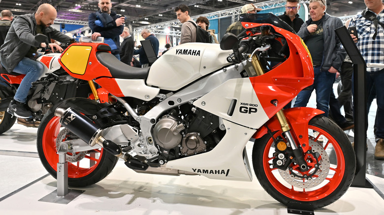 A 2024 Yamaha XSR900 GP with white and orange coloring on display in an show room.