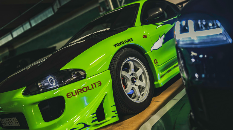 A very green tuner car sits in a garage.