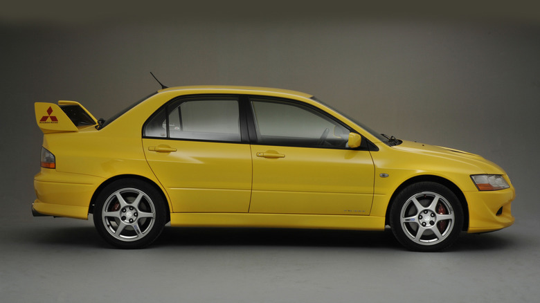 A side view of a yellow Mitsubishi Lancer Evolution shot in a studio setting.