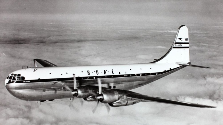 Boeing 377 Stratocruiser passenger plane seen from above left in flight above clouds