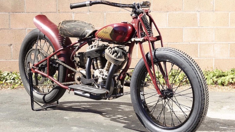 A red 1939 Indian Scout Factory Hill Climber on display in the sun in front of a brick wall.