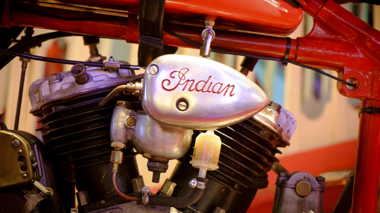 A vintage Indian-brand motorcycle engine sitting beneath a red frame.