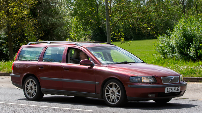 A red Volvo V70 sitting in a parking lot.