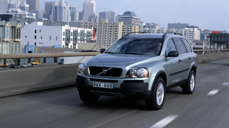 A silver Volvo XC90 driving on a bridge.