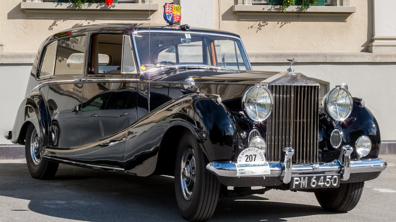 A "Princess Margaret" Rolls-Royce Phantom sits in a parking spot in the sun with chrome shining.