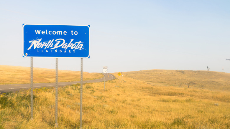 A welcome sign near a road, it says "Welcome to Noth Dakota, Legenday"