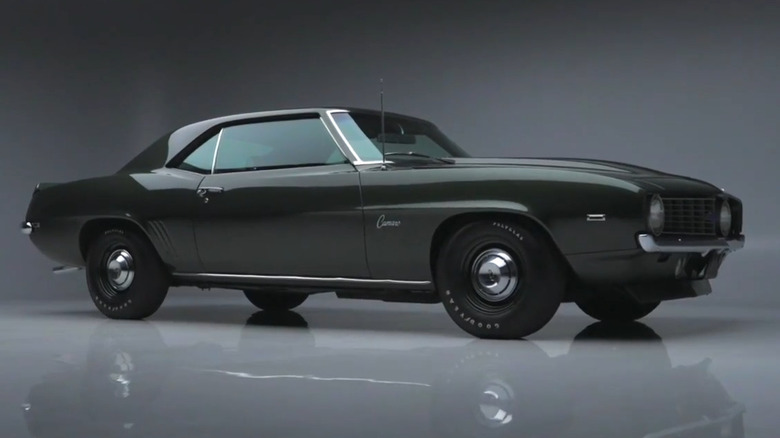 A Fathom Green 1969 Chevrolet Camaro ZL1 coupe with black steel wheels and chrome hubcaps in a studio setting