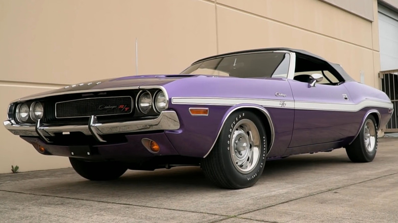 A purple 1970 Dodge Challenger R/T Hemi convertible with white side stripe parked outside a building