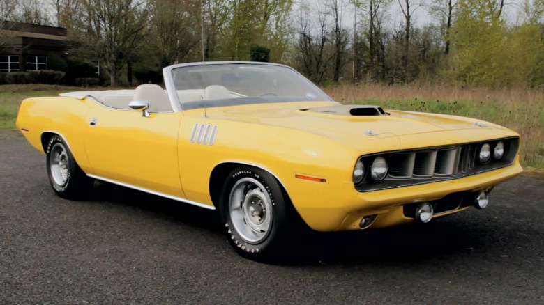 A yellow 1971 Plymouth Hemi 'Cuda convertible with Shaker hood parked outdoors