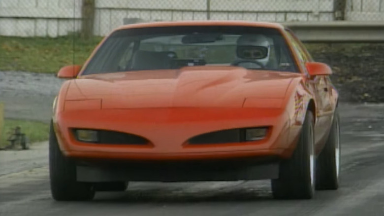 A red 1992 Pontiac SLP Firehawk sports coupe driven on a test track