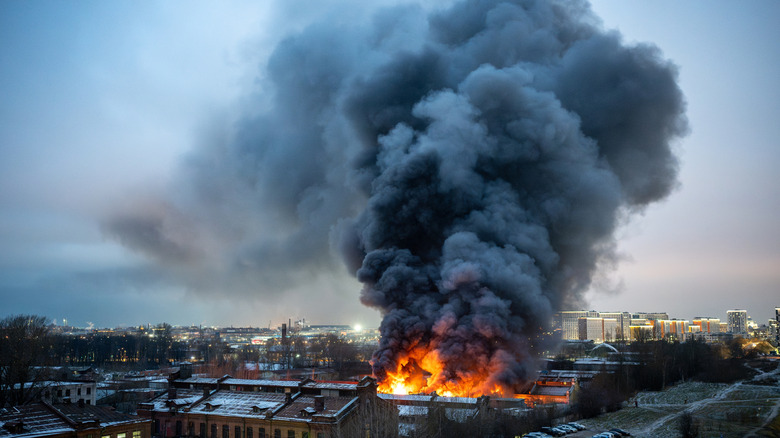 A serious fire belching smoke near a city.
