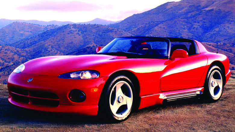 A bright red 1992 Dodge Viper RT/10 roadster parked on a gravel mountain overlook at sunset.